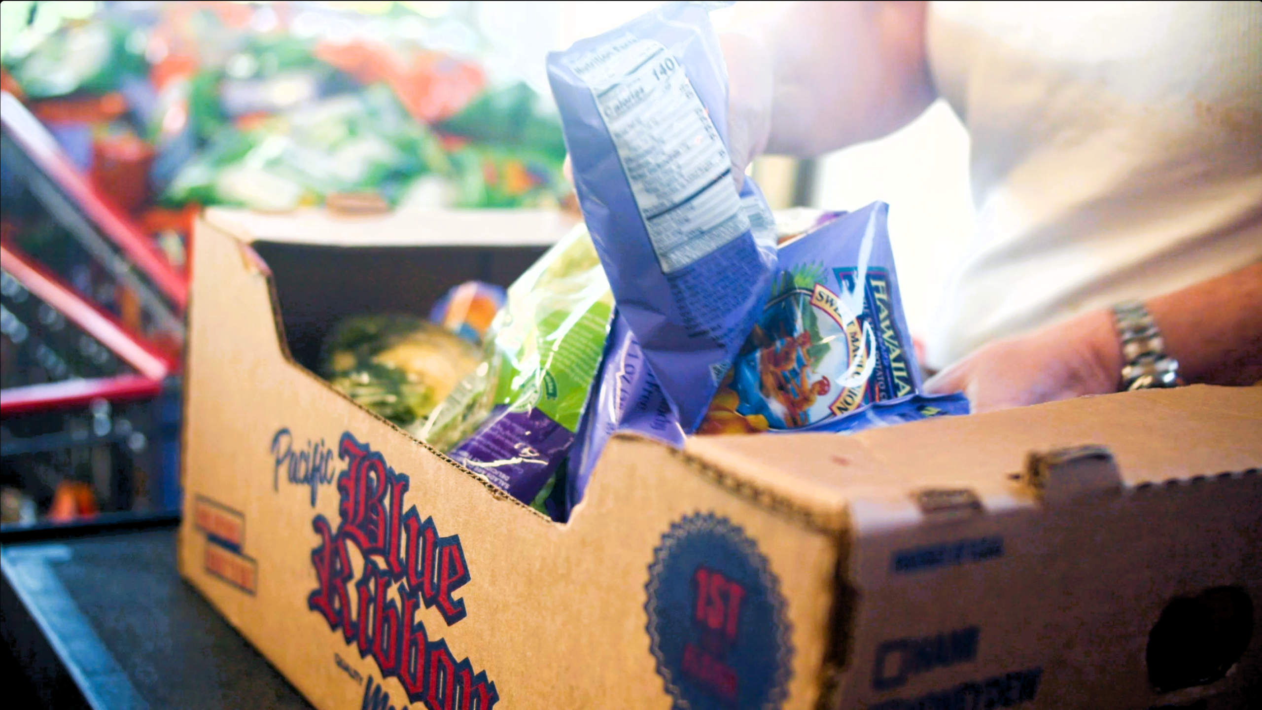 A shopper filling a box of food
